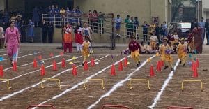Students performing their best the the hurdle race on the ground.